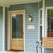 A serene porch with a wooden door that has a rich, warm color and a simple design. The door is set against a backdrop of peaceful blue walls, adding a pop of color to the space. The porch has a relaxed feel with minimal decor, making it a great spot to sit and enjoy the fresh air.