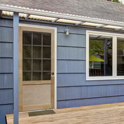 A sturdy wooden door stands out against the calming blue of a porch.